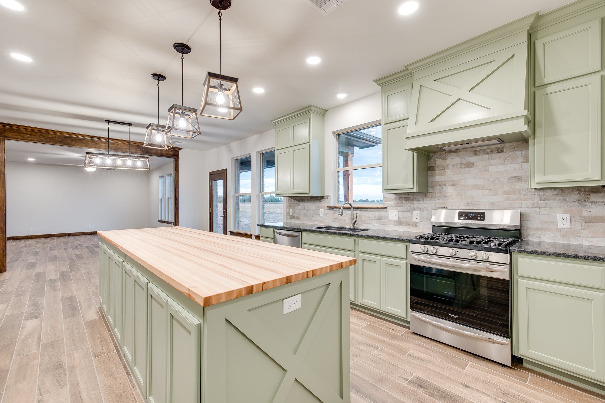 Farmhouse-style kitchen with green cabinetry, butcher block island, and stainless steel appliances in a Crescent, Oklahoma custom home.