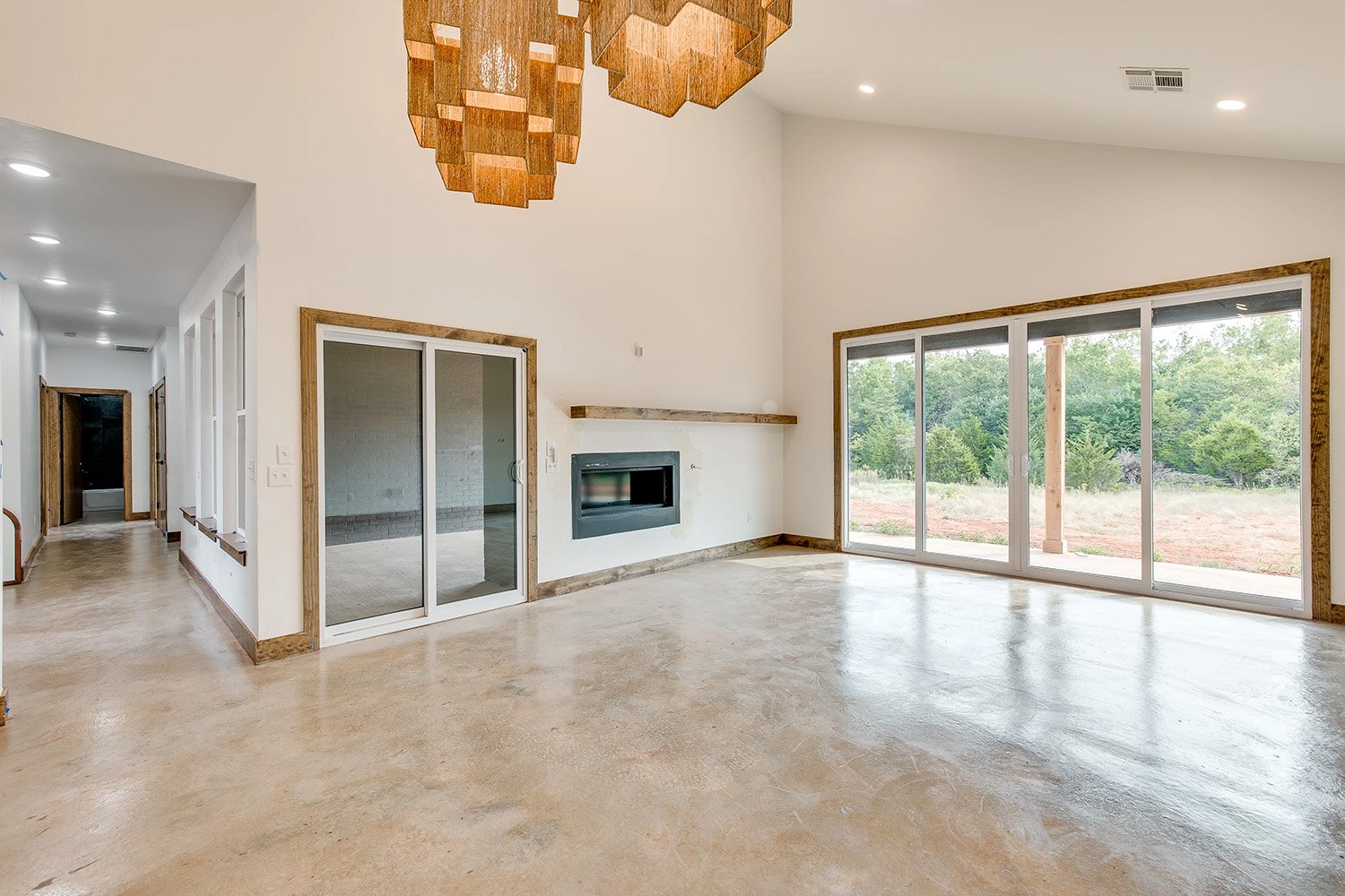Modern living space in Edmond, Oklahoma with large sliding glass doors, a sleek built-in fireplace, natural wood trim, and oversized statement light fixtures providing a warm, inviting atmosphere.