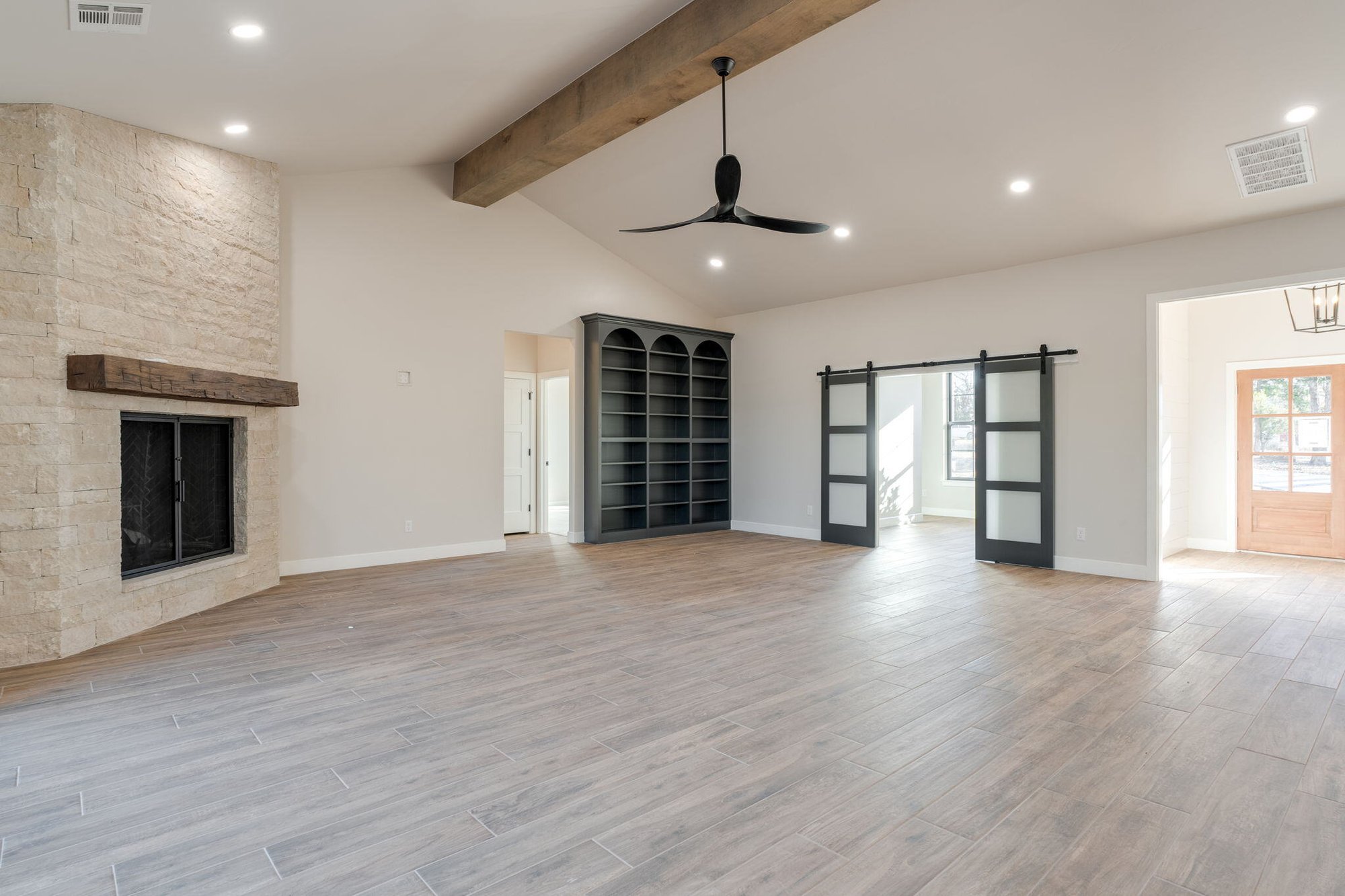 Open floor plan featuring wood-look tile, built-in shelves, and black sliding barn doors.