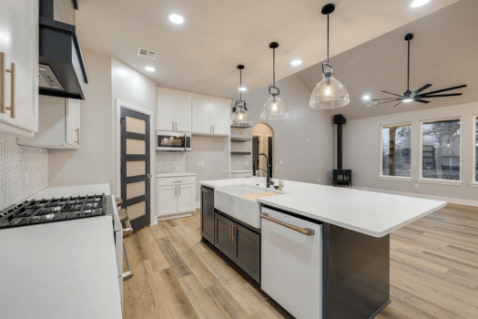 Modern kitchen with large island, pendant lights, and open layout to living area.