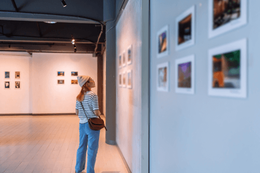 A person viewing framed artworks in a modern art gallery.