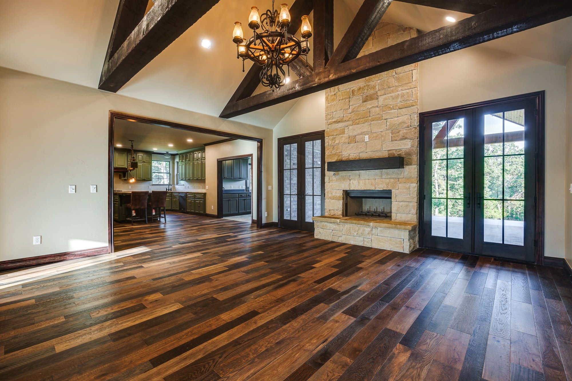 Open floor plan with exposed dark wood beams, French doors, and a warm, inviting feel.
