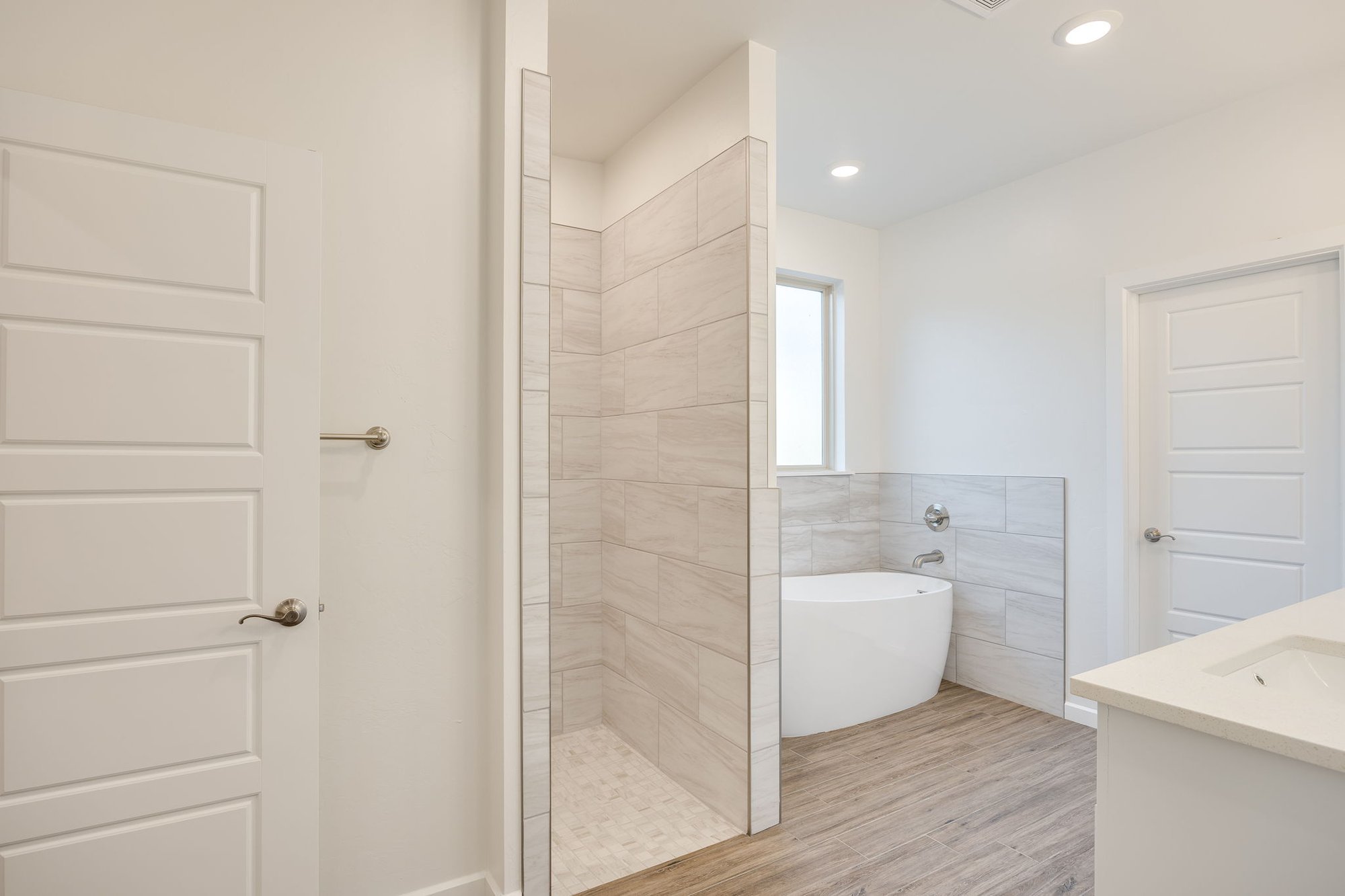 Neutral tile design, wood-look flooring, and a clean, minimalist aesthetic.
