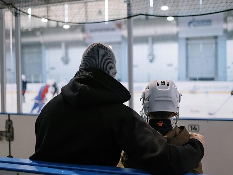 Parent and child watching a hockey practice at Arctic Edge Ice Arena near Seward Oklahoma, enjoying time together at the rink