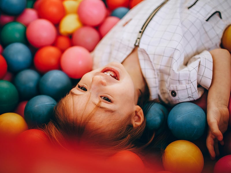 Child smiling while playing in a colorful ball pit at Breakaway Indoor Playground in Edmond, Oklahoma.