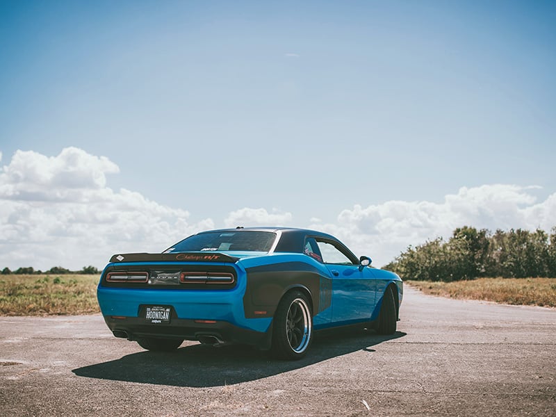 Blue Dodge Challenger parked on an open rural road in Slaughterville, Oklahoma, ready for a scenic drive under a clear sky.