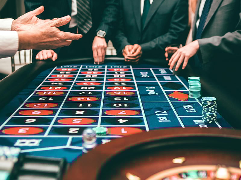 Close-up of a casino roulette game with chips and hands in motion.