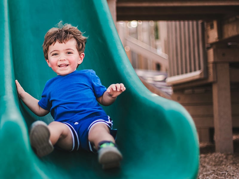 Young boy in a blue shirt enjoying playtime at a park.