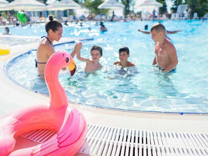Children splashing in a public pool on a sunny day.