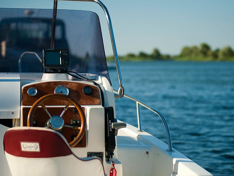 View from the captain’s seat with a steering wheel and calm water in the background.