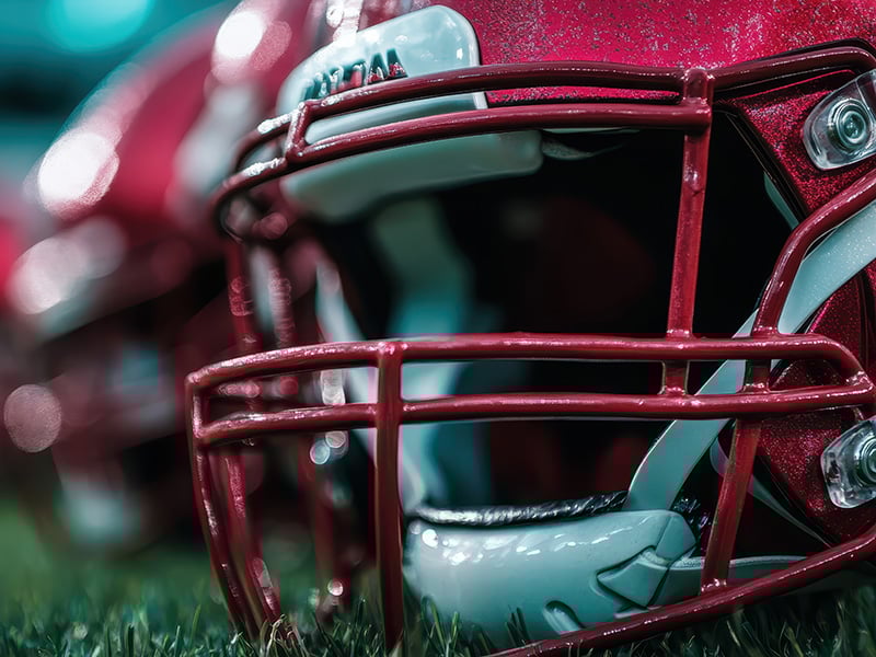 Row of red helmets lined up on the grass before a game.